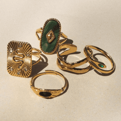 Gold and green gemstone statement rings with intricate designs and embellishments for women. Perfect for custom jewelry collections and unique accessory styles.
