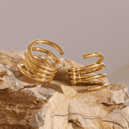 Elegant gold custom jewelry rings on a natural stone display, showcasing luxurious handcrafted designs for unique accessories.