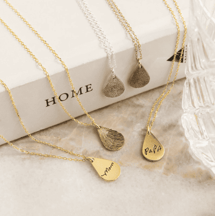 Delicate gold and silver custom jewelry necklaces with engraved and fingerprint designs, perfect for personalized gift-giving.