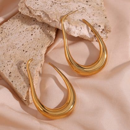 Elegant gold teardrop-shaped earrings on beige silk with textured stone accents, perfect for custom jewelry and statement accessories.