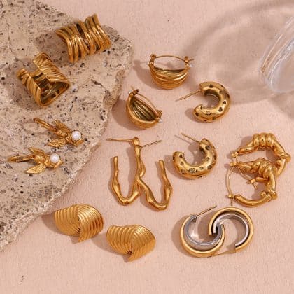 Gold custom jewelry earrings set on a pink background with textured stone accent for stylish and luxurious jewelry display.